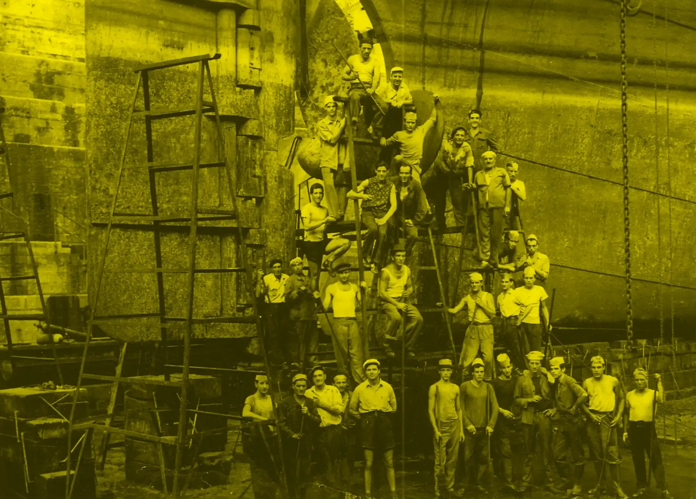 Gli ultimi arsenalotti - Immagine tematica: un gruppo di uomini, uno sopra l'altro a formare una piramide, al fianco di una chiglia navale. La foto è con dominante di colore giallo.