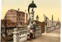 Statua della Madonna a Chioggia con vicino due bambini e delle barche nello sfondo.